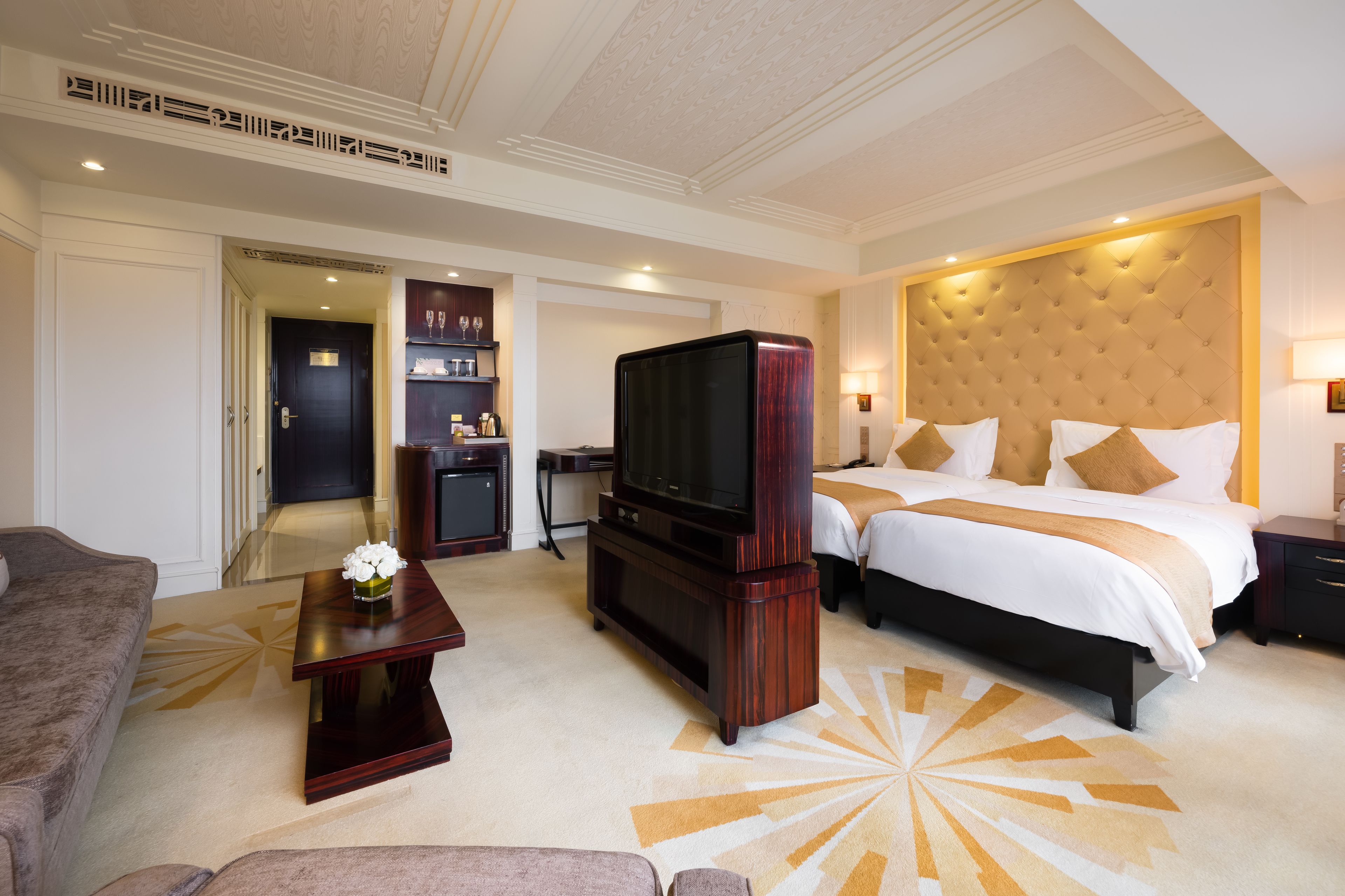 A hotel room with a large bed, a TV, a desk, and a sofa.