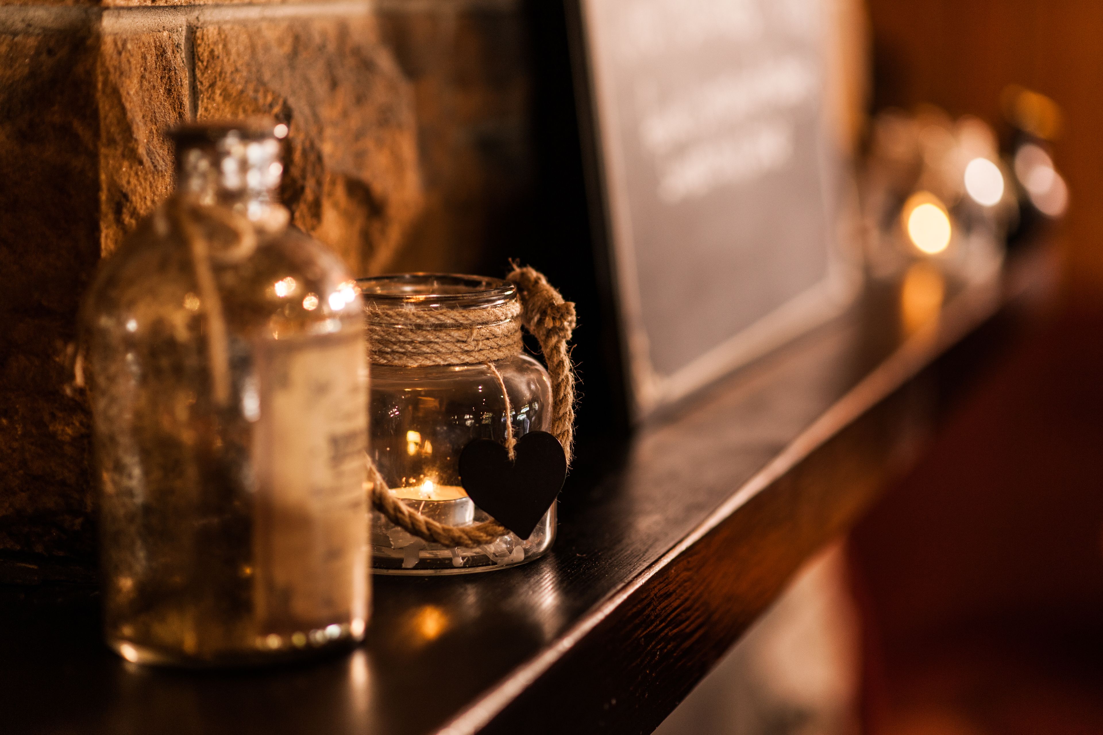 A shelf with a glass bottle, a jar with a heart-shaped ornament, and a candle.
