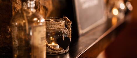 A shelf with a glass bottle, a jar with a heart-shaped ornament, and a candle.