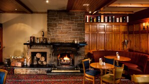 Une pièce chaleureuse avec une cheminée en pierre, des meubles en bois et une bibliothèque remplie de divers objets.