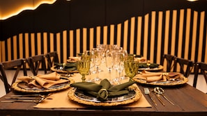 Mesa formal dispuesta para comer, con varios cubiertos, copas y utensilios.