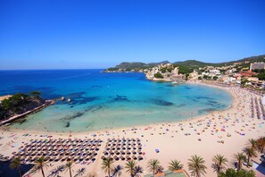 A beach with numerous umbrellas and sun loungers, a clear blue sea, and buildings in the background. - Valentin Somni Hotels & Suites – Adults Only +16 (Calvia)