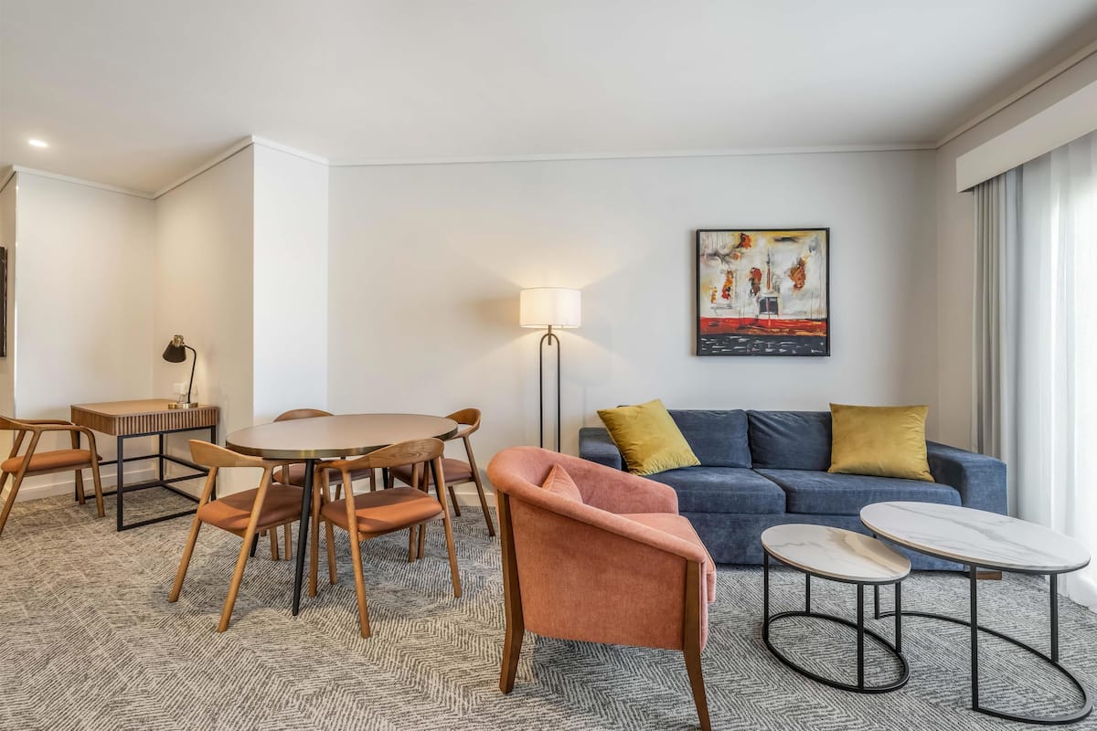 A modern living room with a blue sofa, a round table, and two chairs.