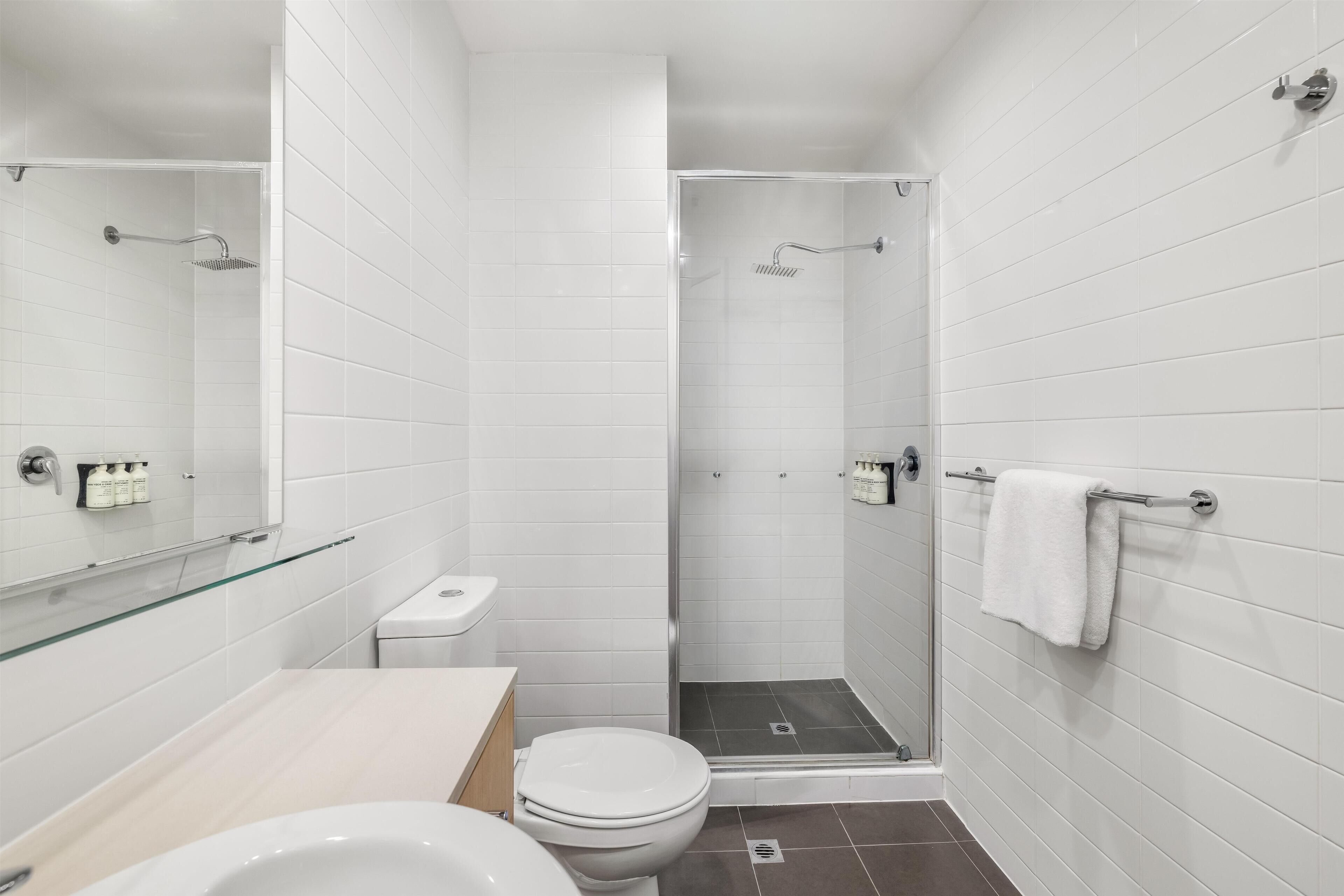 Un baño moderno con ducha de vidrio, inodoro y lavamanos.