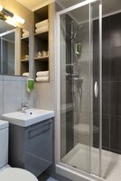 Un baño moderno con ducha envuelta en vidrio, un lavabo blanco y un espejo sobre el lavabo.
