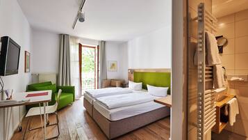 Habitación de hotel con cama, escritorio, silla, televisor y baño con perchero.