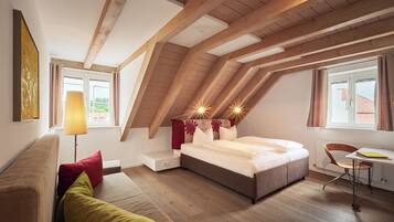 A bedroom with a loft-style ceiling, a bed, a desk, and a chair.
