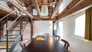 Un comedor amplio con una mesa de madera oscura, varias sillas y una escalera con barandillas de metal.