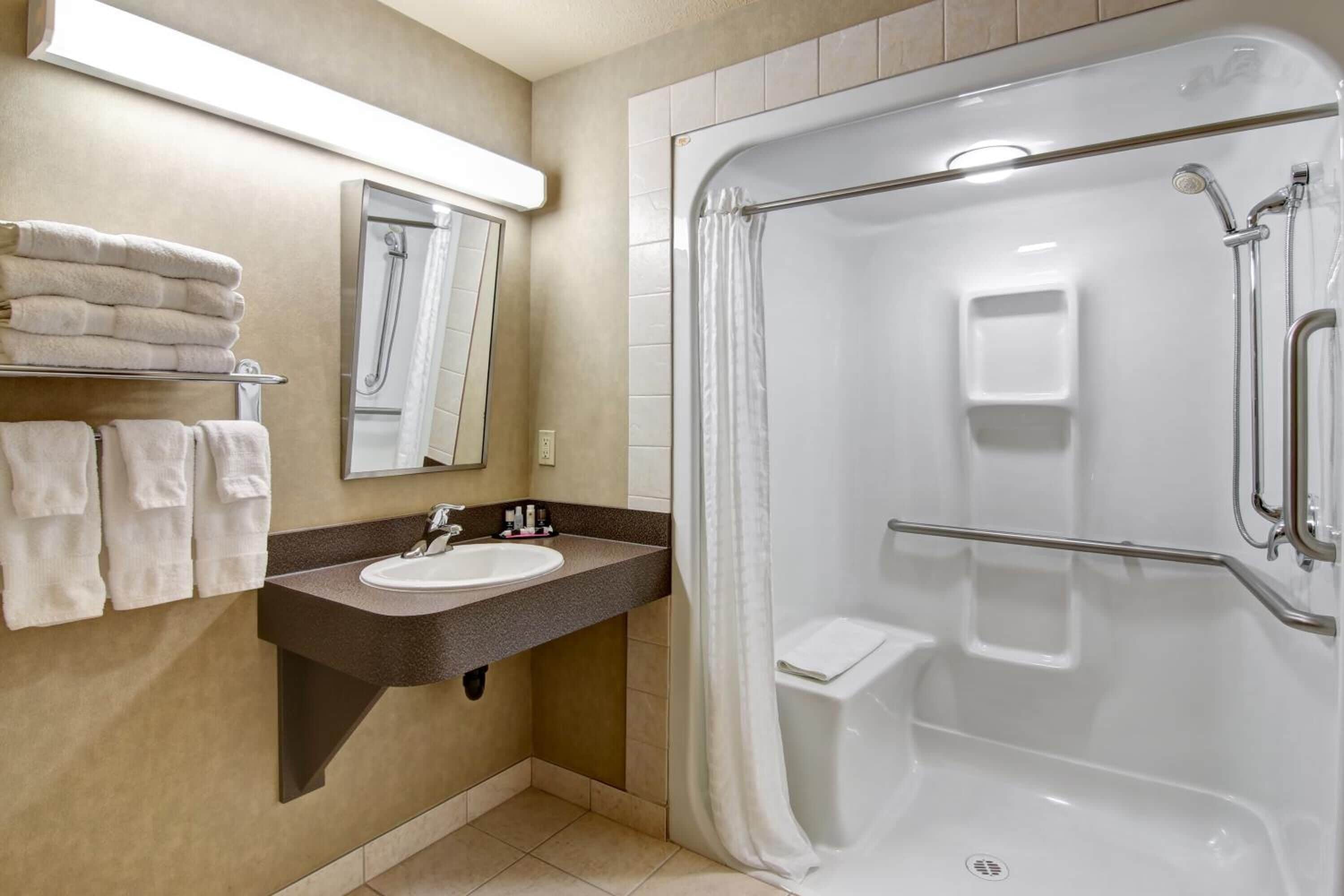 A modern bathroom with a built-in sink, a shower with a glass door, and a towel rack with neatly folded towels.