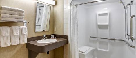 Une salle de bain moderne avec un lavabo intégré, une douche dotée d’une porte en verre et un porte-serviettes où les serviettes sont soigneusement pliées.