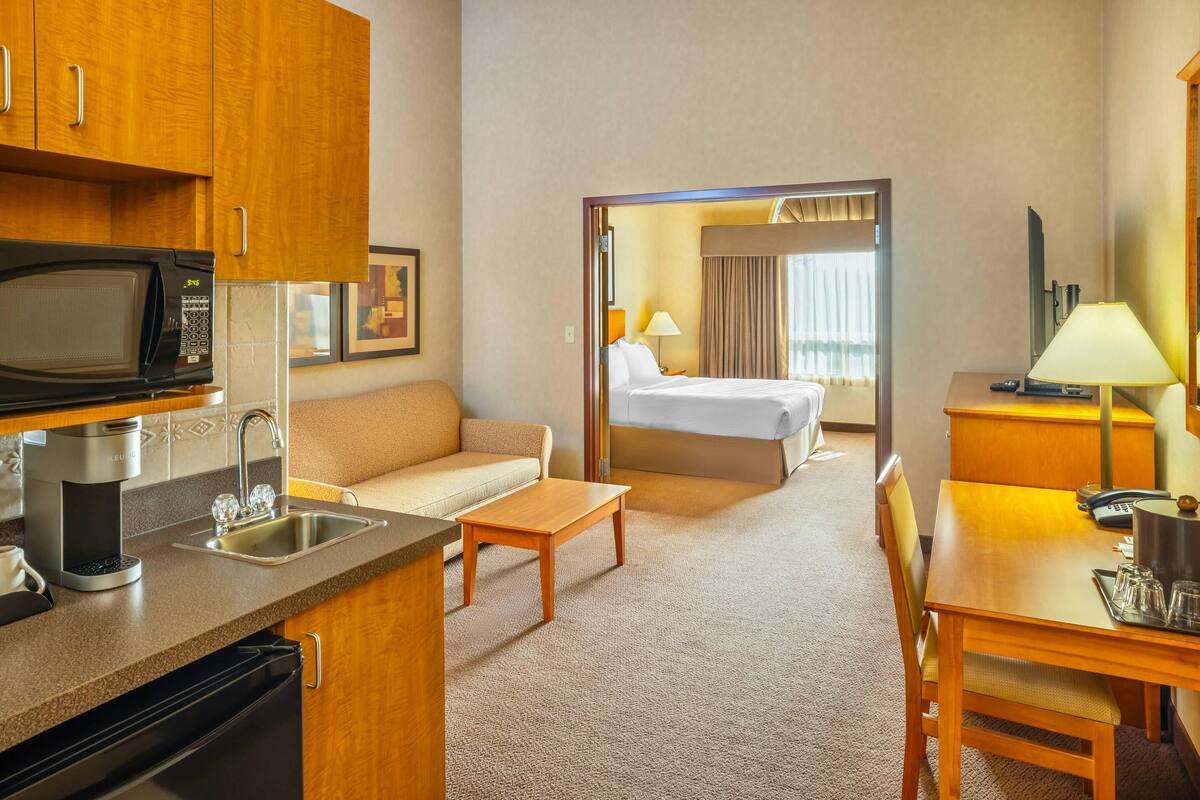 Une chambre d’hôtel équipée d’une kitchenette, d’un lit, d’un canapé, d’une table à manger et d’un miroir.