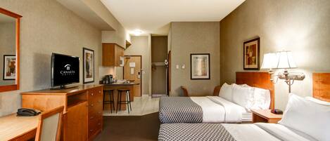 A hotel room with a bed, desk, and kitchenette.