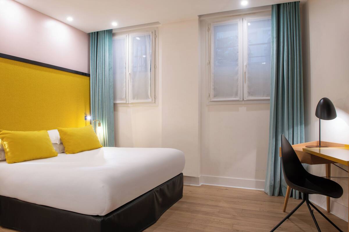 A hotel room with a bed, a desk, and a chair.