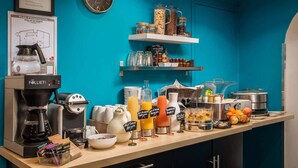 A breakfast bar with a coffee machine, juice dispensers, and various food containers.