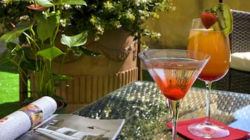A table with two drinks, a magazine, and a potted plant.