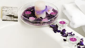A bathroom with a white bathtub, a glass bowl with a candle, and a white towel.