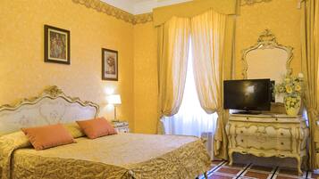 Una habitación de hotel con una cama grande, televisión, cómoda y ventana con cortinas.