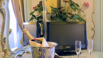 A room with a vintage mirror, a television, a bottle of champagne, and scattered rose petals.