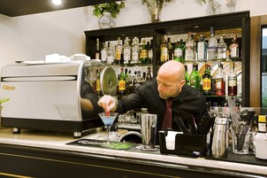 Un espace bar équipé d’une machine à café, d’étagères remplies de bouteilles d’alcool et d’outils de bar.