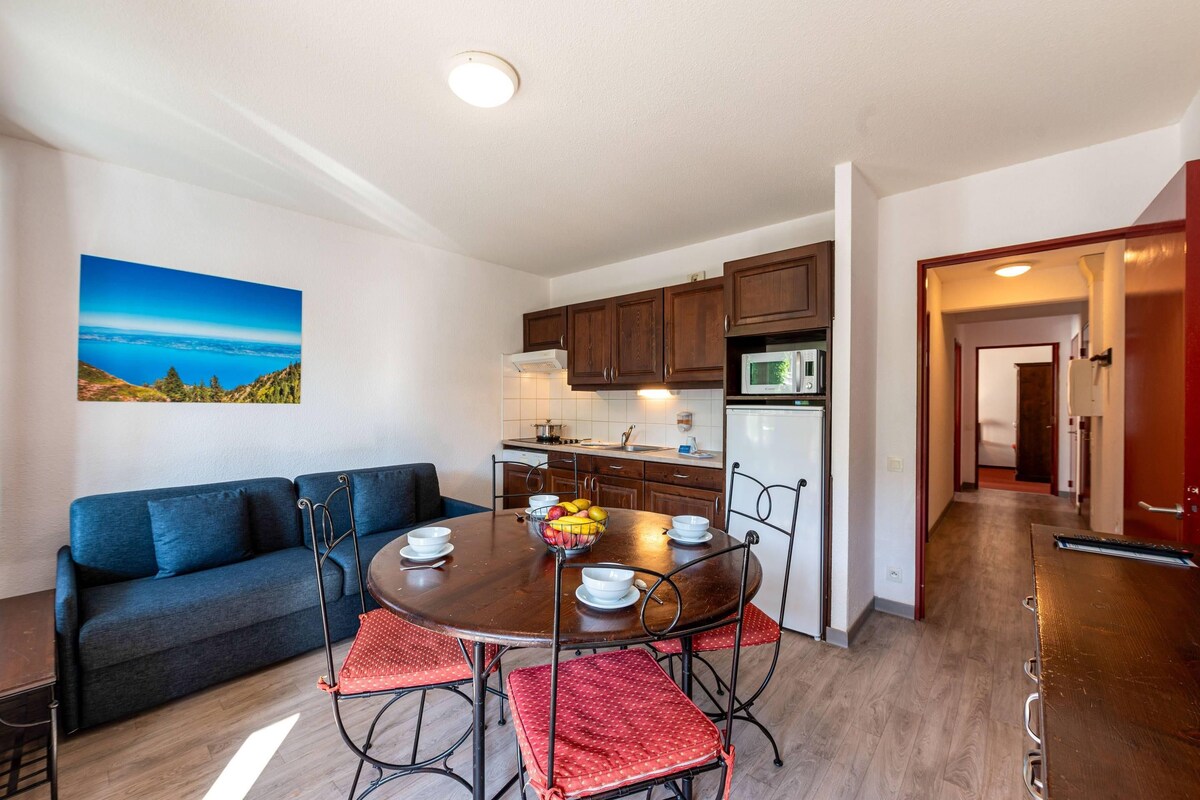 A modern kitchen with wooden cabinets, a dining table with chairs, and a view of the outdoors.