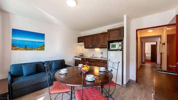 A modern kitchen with wooden cabinets, a dining table with chairs, and a view of the outdoors.