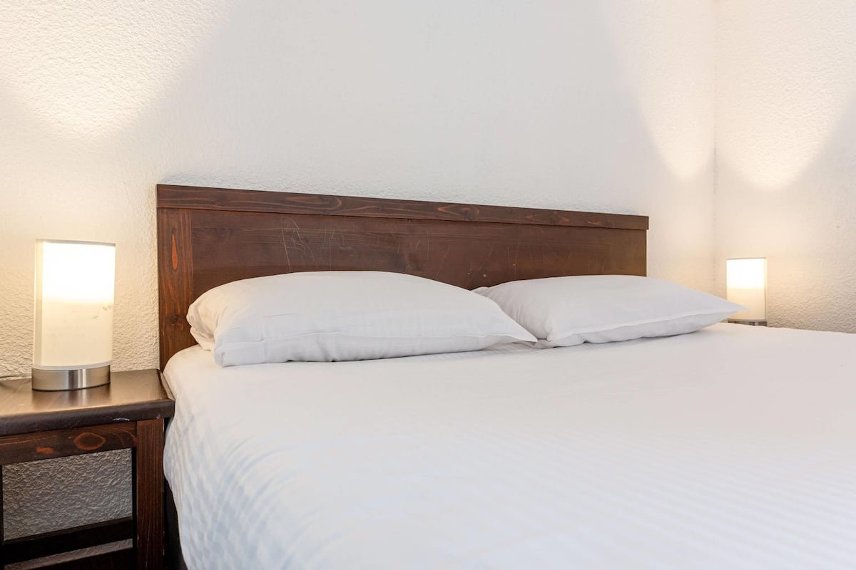 A neatly made bed with white linens and two bedside lamps on wooden nightstands.