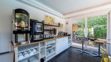 A breakfast bar with coffee machines, a fruit display, and a view of the outdoors.