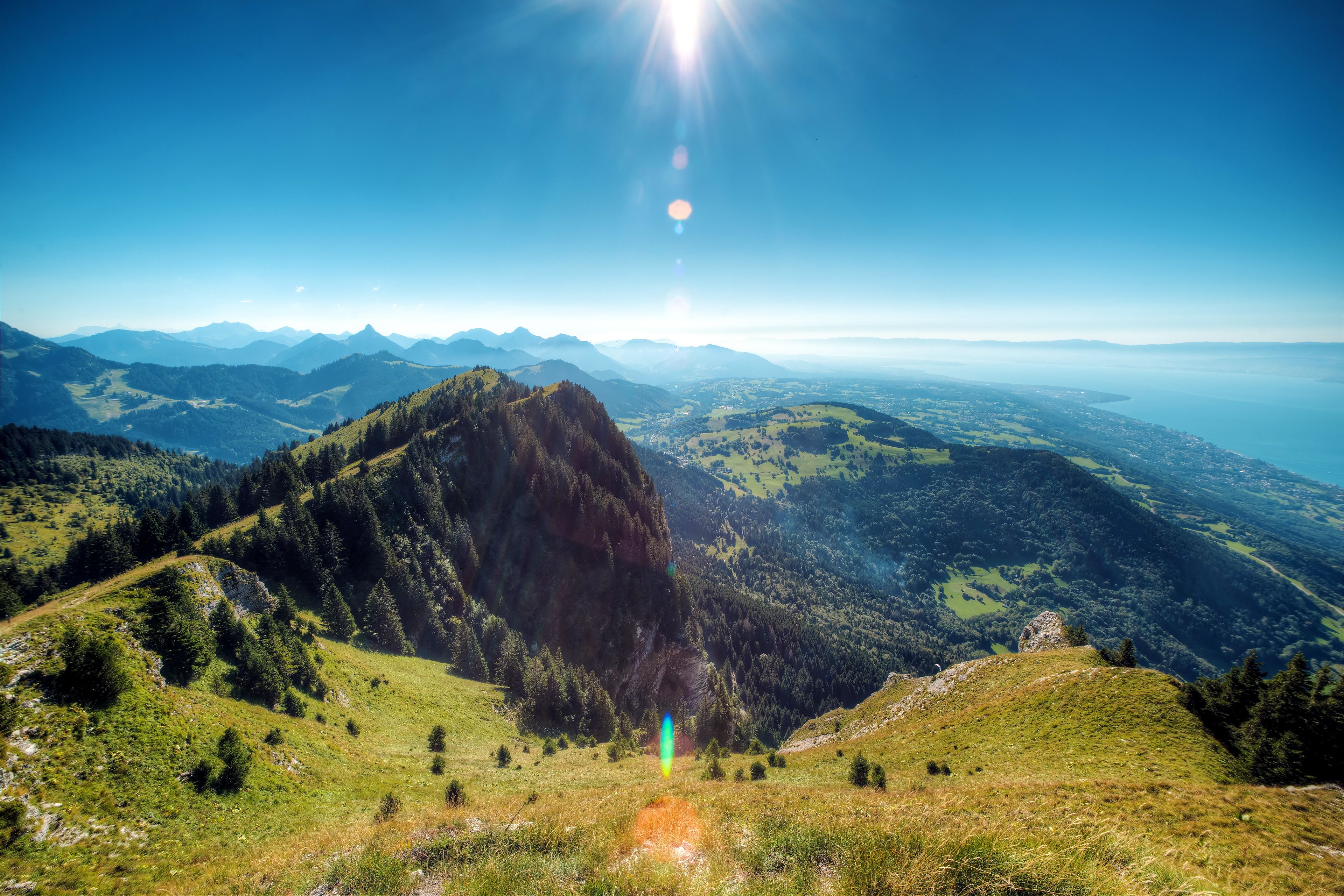 A panoramic view of a mountainous landscape with a prominent rocky peak and a clear sky.