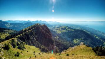 A panoramic view of a mountainous landscape with a prominent rocky peak and a clear sky.