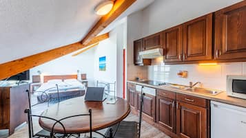 Una cocina moderna con armarios de madera, horno empotrado y comedor con una mesa redonda y sillas de metal.