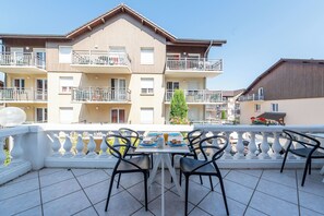 A balcony with a table set for breakfast, overlooking a multi-story building with balconies. - Zenitude Evian Les Terrasses du Lac (Evian-les-Bains)