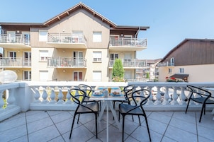 Un balcón con una mesa dispuesta para el desayuno, con vista a un edificio de varios pisos con balcones.