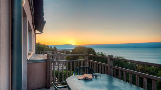 A balcony with a table, chairs, and a pair of sunglasses. - Zenitude Evian Les Terrasses du Lac (Evian-les-Bains)