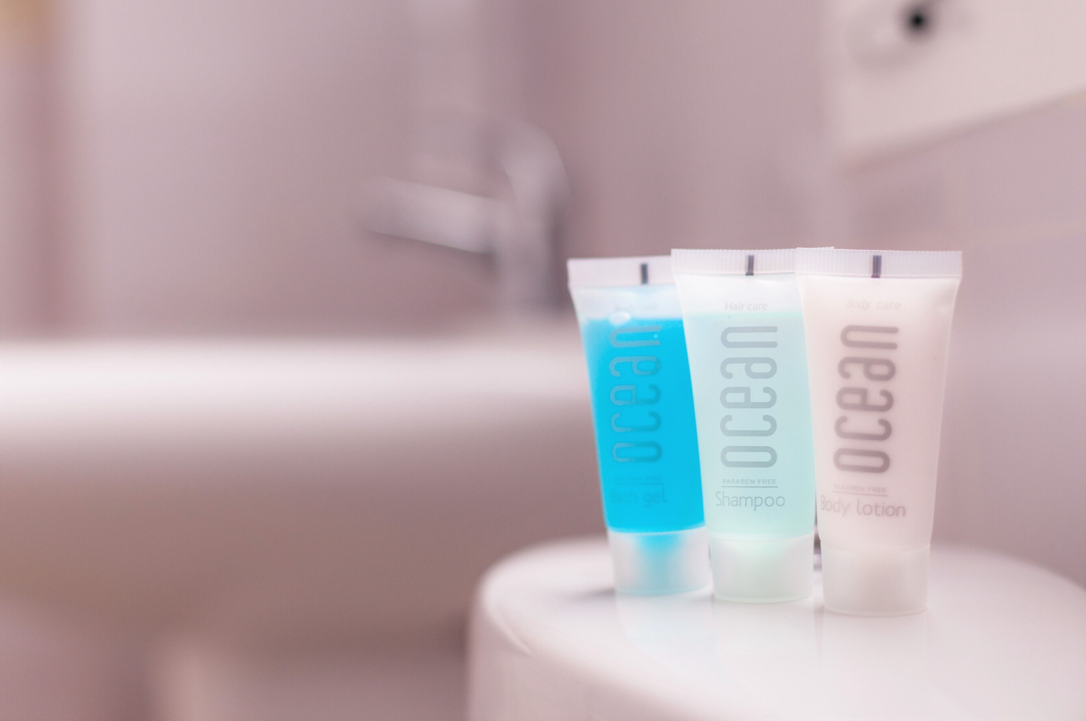 Three toiletry items on a white surface with a blurred background.