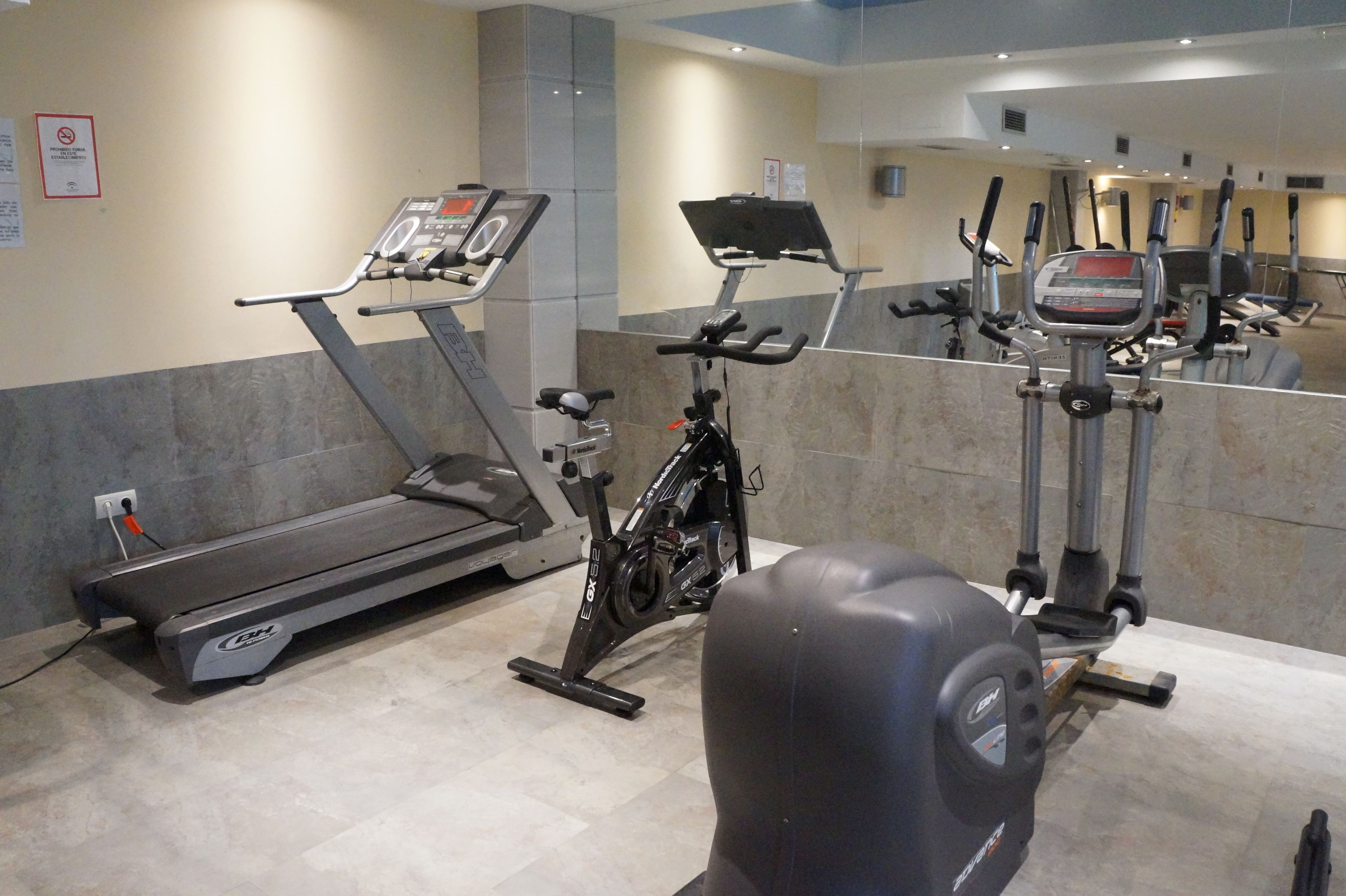 Une salle de sport équipée d’un tapis de course, d’un vélo d’appartement et d’un appareil d’entraînement elliptique.