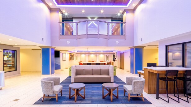 Un hall d’entrée spacieux avec un espace salon central, un bar et un plafond haut orné d’un lustre.