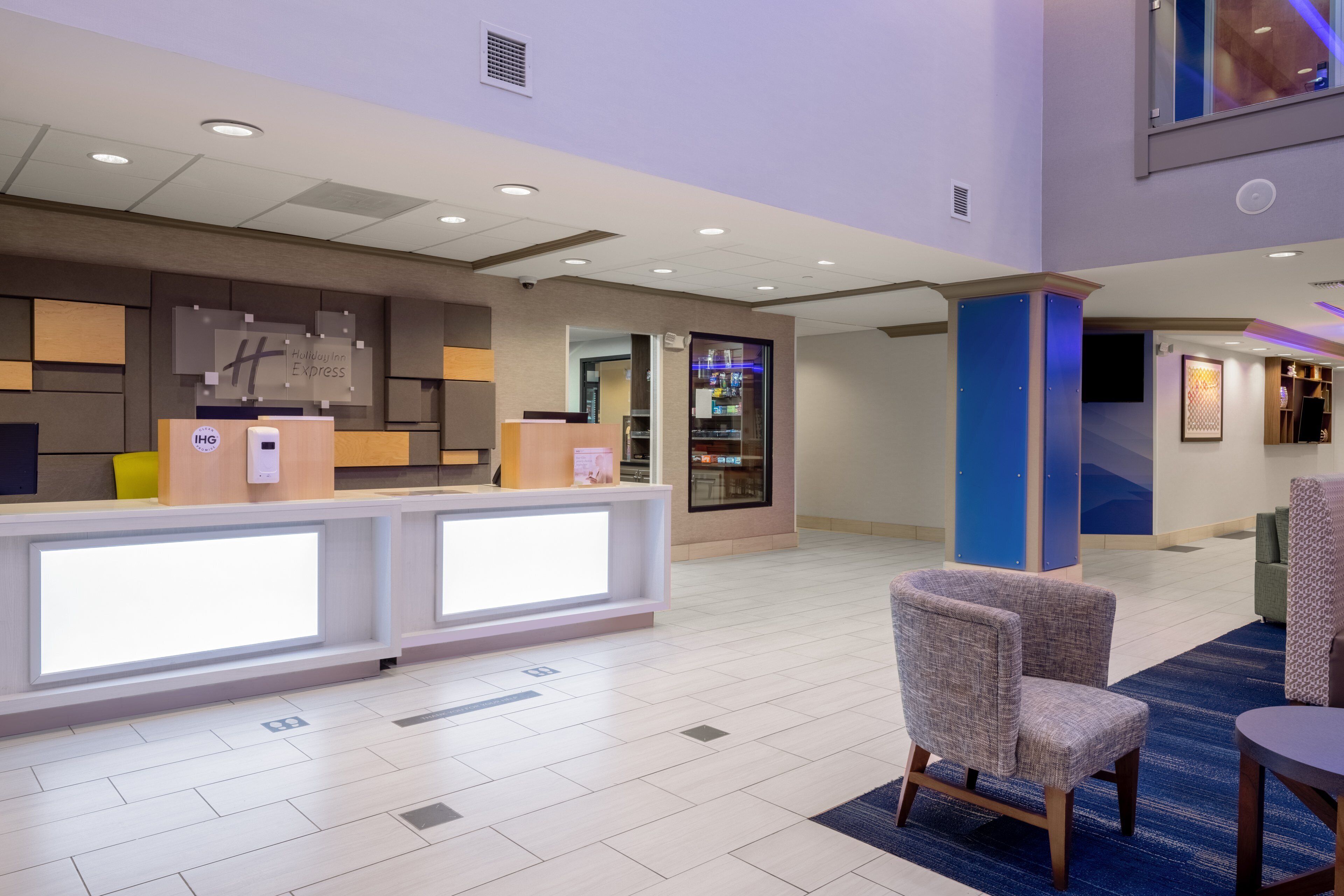 A hotel lobby with a reception desk, seating area, and a large window.