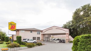 A Super 8 motel with a large sign, a covered parking area, and a well-maintained lawn. - Super 8 by Wyndham Lake Country/Winfield Area Airport North (Lake Country)