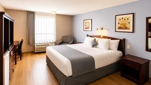 A hotel room with a bed, a desk, a chair, a TV, and two framed pictures on the wall. - Super 8 by Wyndham Lake Country/Winfield Area Airport North (Lake Country)