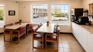 A hotel room with a dining area, a coffee station, and large windows offering a view of the street. - Super 8 by Wyndham Lake Country/Winfield Area Airport North (Lake Country)