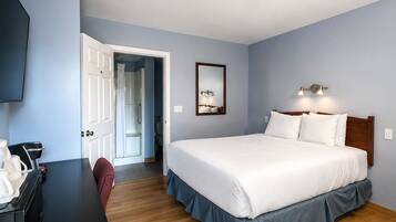 Une chambre d’hôtel équipée d’un lit, d’un bureau, d’une chaise, d’une télévision et d’une porte donnant accès à une salle de bain.