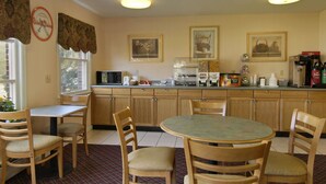 A dining area with wooden chairs and tables, a kitchen counter with appliances, and framed pictures on the wall. - Howard Johnson by Wyndham Williamstown (Williamstown)