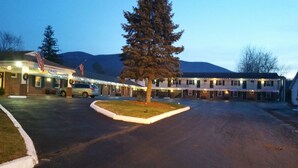 A motel with multiple rooms, a parking area, and a large tree in the foreground. - Howard Johnson by Wyndham Williamstown (Williamstown)