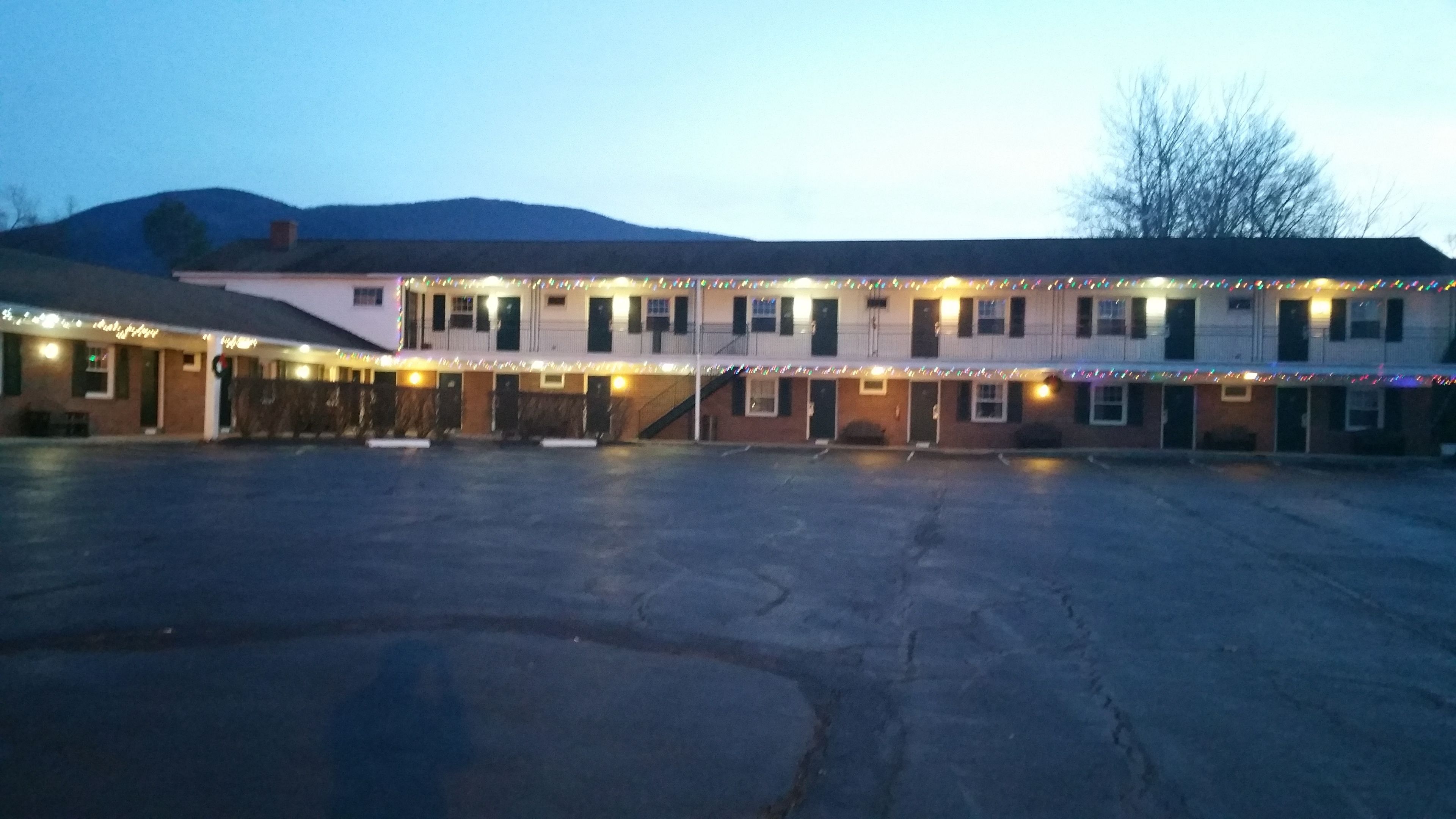 A motel with a large parking lot and a building with multiple windows and doors.