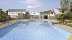 A rectangular swimming pool with a wooden deck surrounding it. - Howard Johnson by Wyndham Williamstown (Williamstown)
