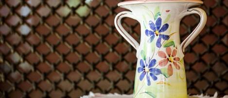 Una jarra de cerámica con diseños florales sobre un mantel.