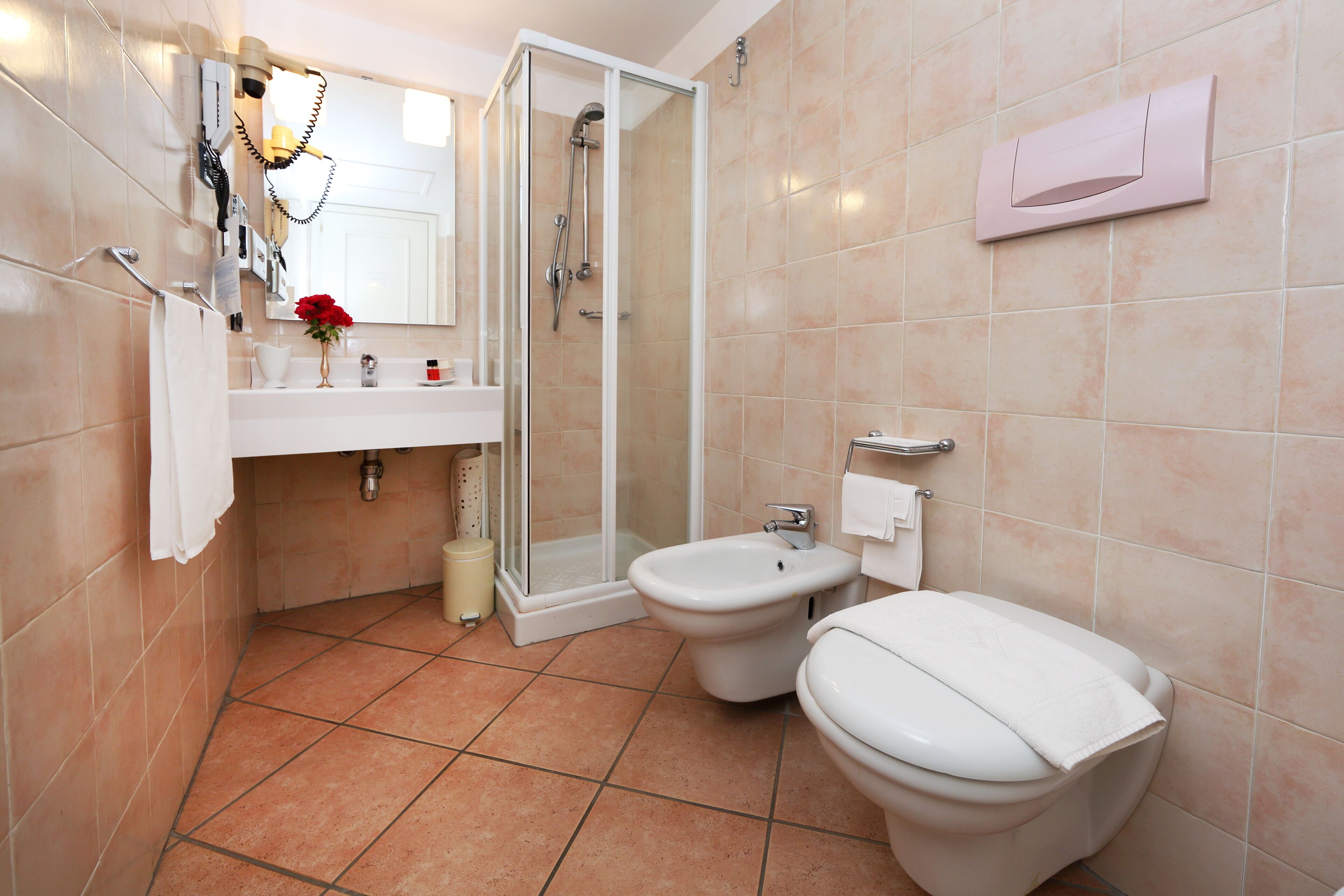 Une salle de bain avec deux toilettes, une douche, un lavabo et un miroir.