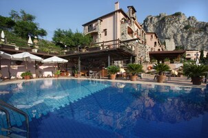 A pool area with a stone building, outdoor seating, and potted plants.
