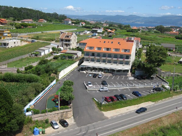 Un hotel con estacionamiento, parque infantil y vistas del paisaje circundante.
