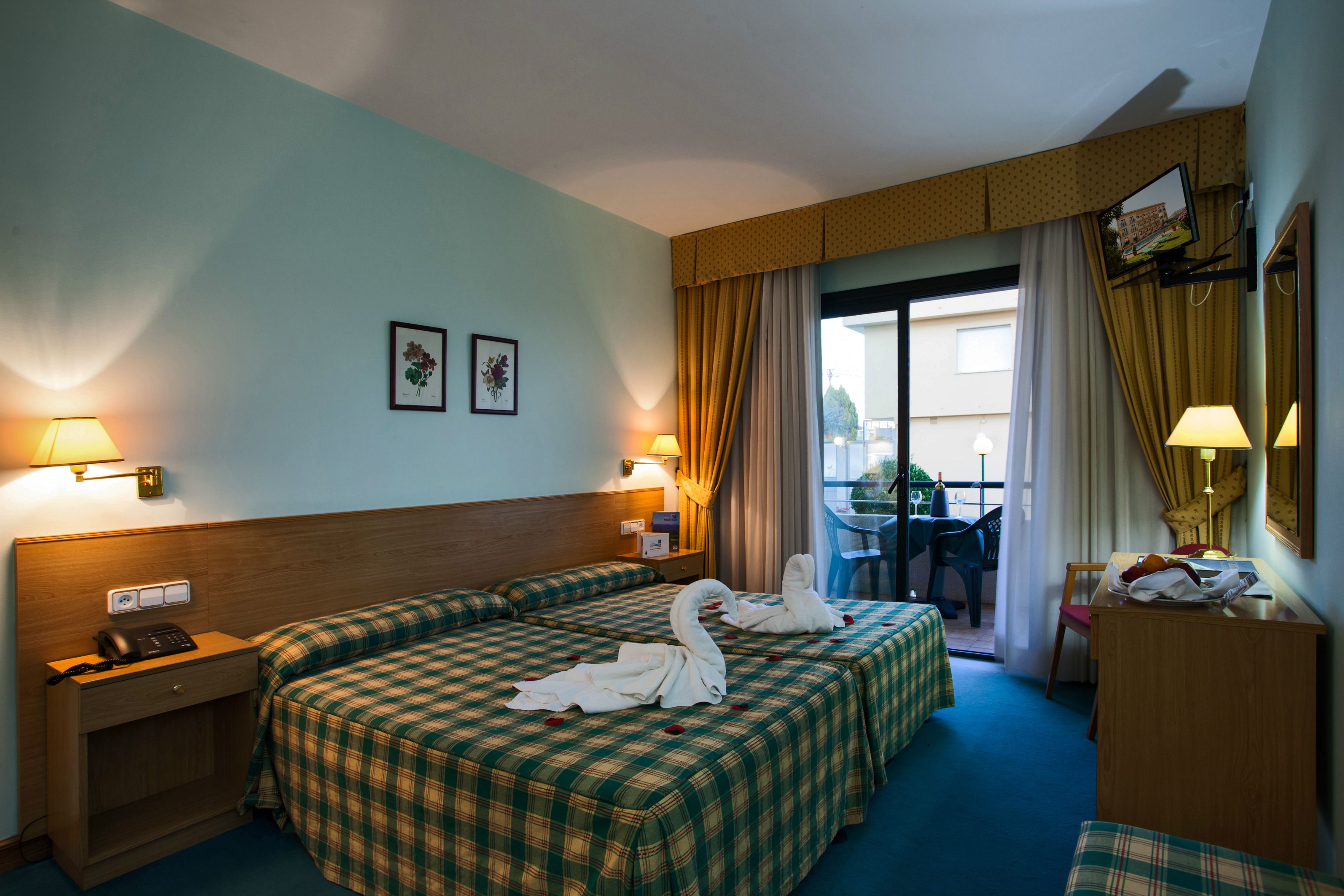 A hotel room with two beds, a desk, a chair, a telephone, and a window with curtains.